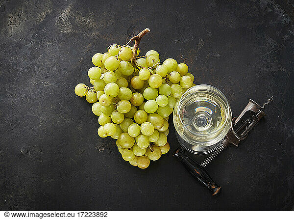 Studio shot of fresh grapes  corkscrew and glass of white wine