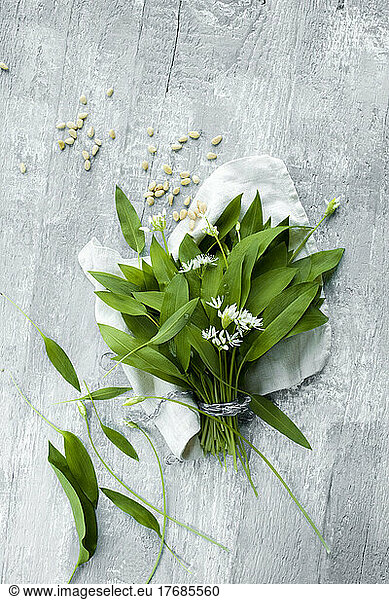 Studio shot of fresh ramson leaves and pine nuts lying against wooden surface