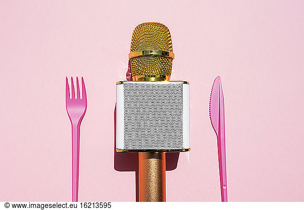 Studio shot of golden microphone and plastic cutlery
