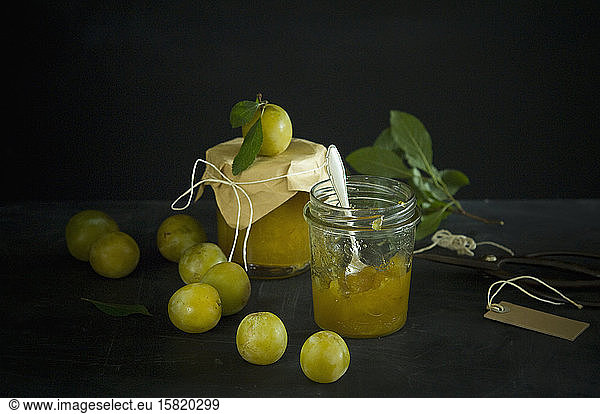 Studio shot of greengages and jars of homemade plum jam