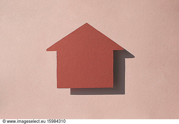 Studio shot of house shaped paper cut against pastel pink background