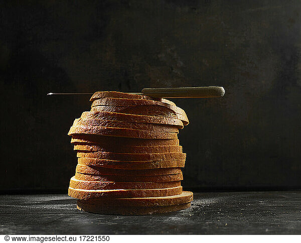 Studio shot of kitchen knife lying on top of stack of fresh bread slices