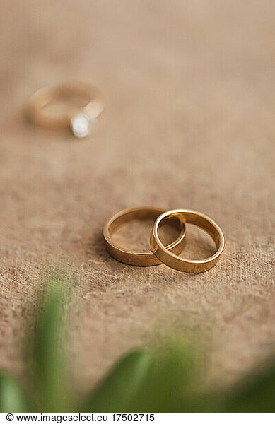 Studio shot of pair of golden wedding rings lying against brown background