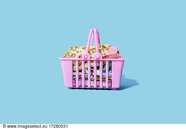 Studio shot of pink shopping basket filled with clothing