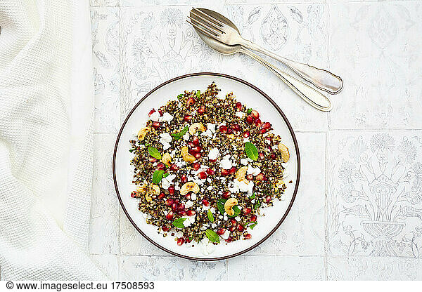 Studio shot of plate of quinoa salad with feta cheese  pomegranate seeds and cashews