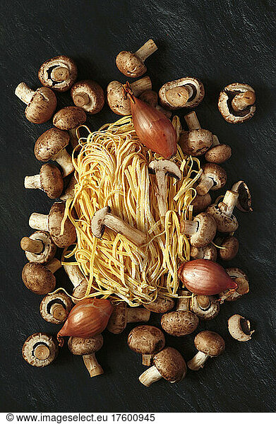 Studio shot of raw onions  mushrooms and fettuccine pasta