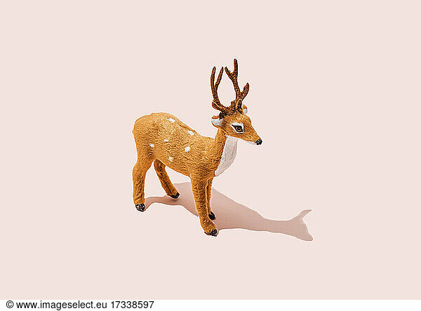 Studio shot of reindeer figurine standing against pink background