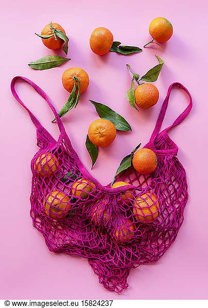 Studio shot of ripe clementines and eco-friendly reusable mesh bag