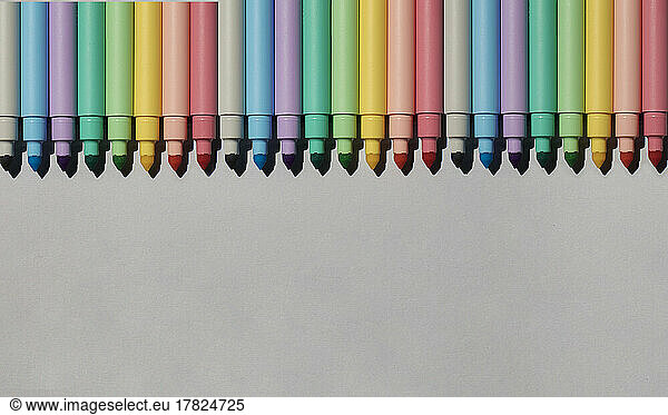 Studio shot of row of colorful felt tip pens lying against gray background