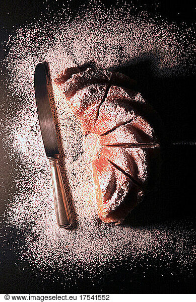 Studio shot of table knife and Kugelhupf cake with powdered sugar