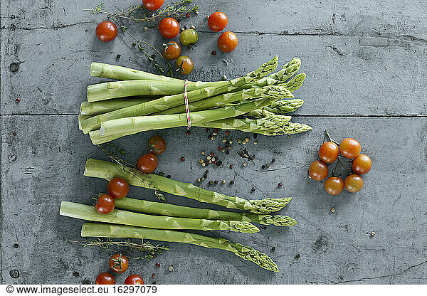 Studio shot of tomatoes  peppercorns  thyme and green asparagus bundles