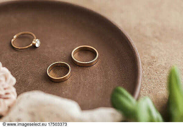Studio shot of tray with engagement ring and golden wedding rings
