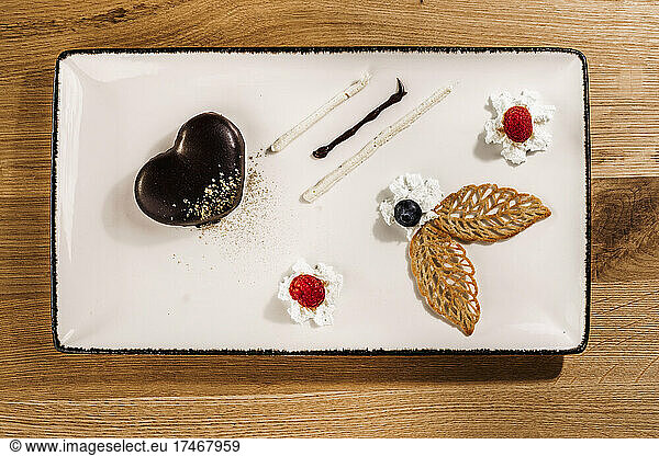 Studio shot of tray with finely presented chocolate cake with fruit and whipped cream additions
