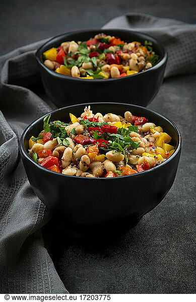 Studio shot of two bowls of bean stew with bell and chili peppers  quinoa and parsley