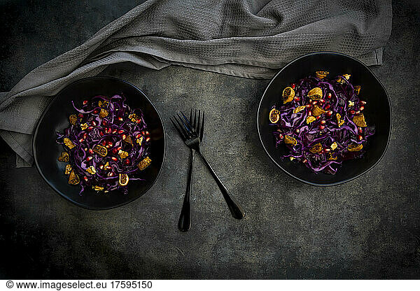 Studio shot of two bowls of vegan salad with red cabbage  pomegranate seeds  dried figs and walnuts