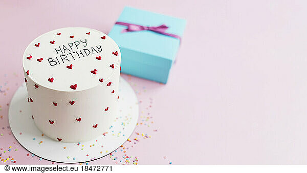 Studio shot of white colored birthday cake and wrapped gift