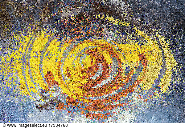 Studio shot of yellow and orange spices mixing together in swirl pattern