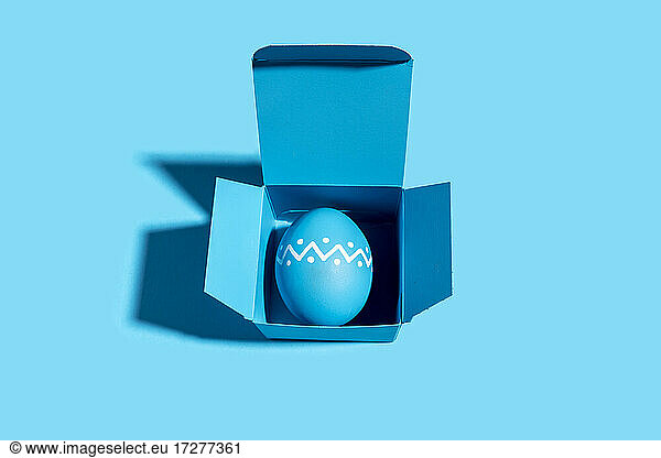 Studioaufnahme eines blauen Ostereis in einer blauen Schachtel