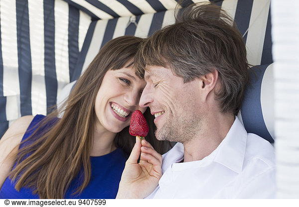 Stuhl lächeln Strand Erdbeere Dach essen essend isst Peddigrohr