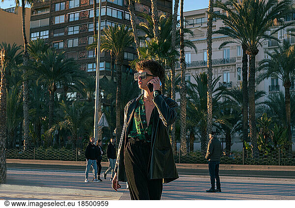 Stylish alternative gay man with sunglasses talks through his phone
