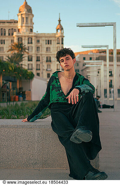 Stylish alternative gay youth man poses in a city looking at camera