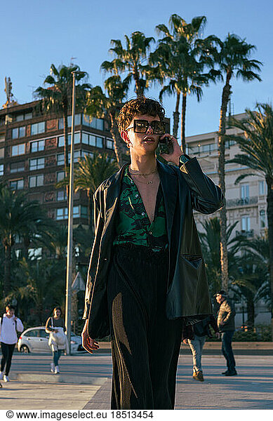 Stylish alternative man with sunglasses talks through his phone