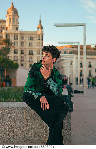 Stylish alternative youth man poses in a city at sunset
