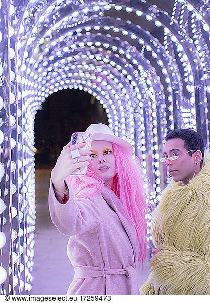 Stylish couple taking selfie under arch lights
