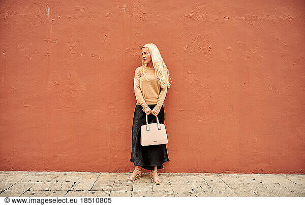 Stylish female standing by wall