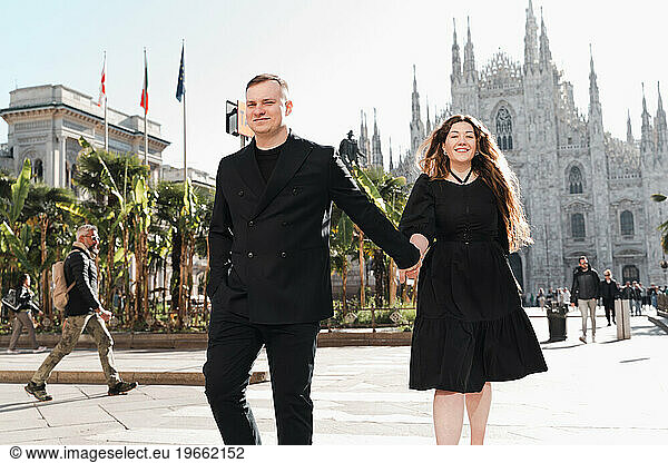 Stylish girl and guy in black walking in the center of Milan