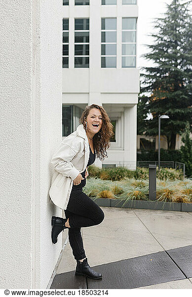 Stylish grown woman with long hair looking into camera laughing