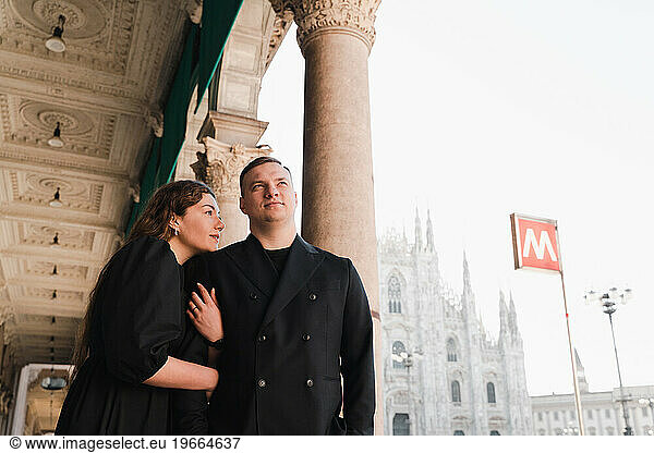 Stylish man and woman in love stand near Duomo metro station in Milan