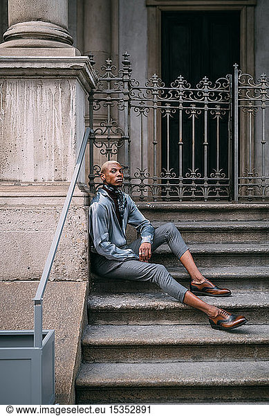 Stylish man sitting on steps of period building  Milan  Italy