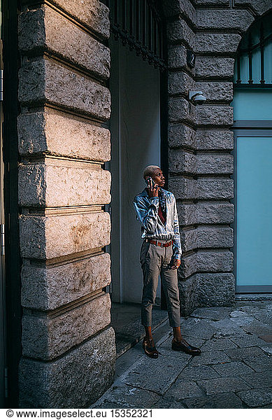 Stylish man using cellphone by period building  Milan  Italy