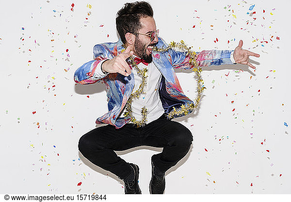 Stylish man wearing a colorful suit and sunglasses celebrating a party and jumping