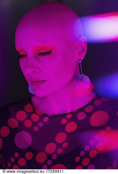 Stylish serene woman with shaved head in red light