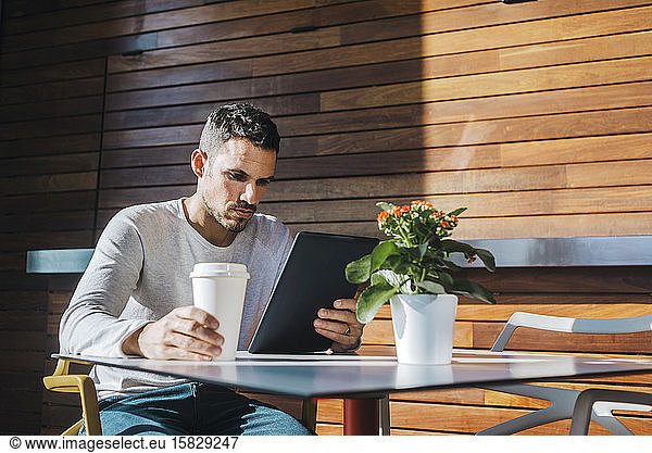 Stylish young man sitting on couch in a cafe using tablet