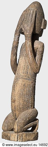 SUBSAHARISCHE STAMMESKUNST  Figur der Dogon  Mali um 1900. Kniende mÃ¤nnliche Figur aus Hartholz geschnitzt  die erhobenen HÃ¤nde das Gesicht verhÃ¼llend. Der Torso mit aufwÃ¤ndigen Stammesnarben Ã¼berzogen. Vorderseite stÃ¤rker patiniert  Alters- und leichte FraÃŸspuren  etwas rissig. HÃ¶he 79 cm