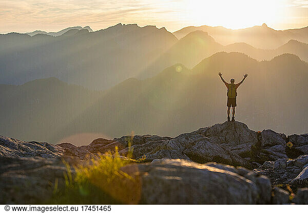 Successful man standing on rocky mountain summit.