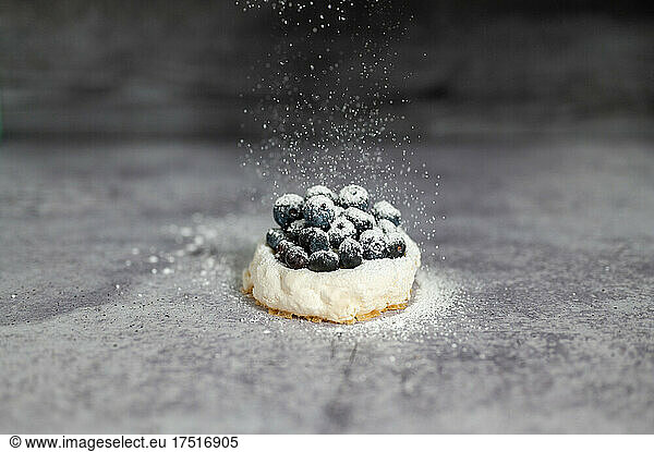 Sugar falling on a blueberry Pavlova