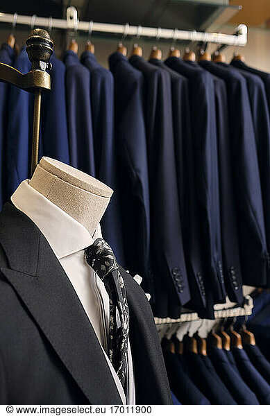 Suit on mannequin and blazers on rack in tailors boutique