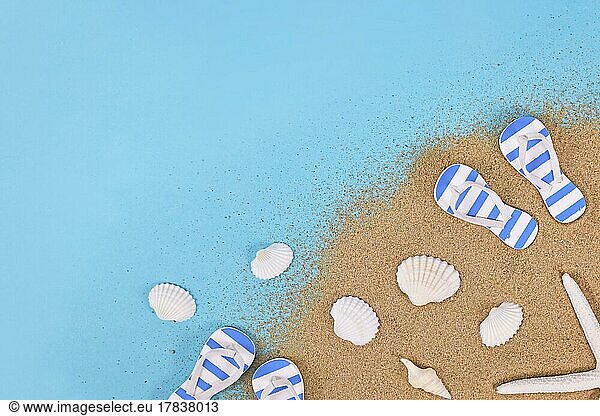 Summer shoes  seashells  starfish and sand in corner of blue background