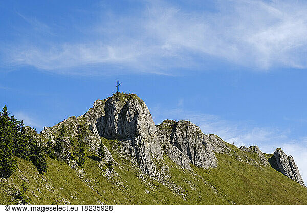 Summit cross on top of Tegelberg mountain under blue sky