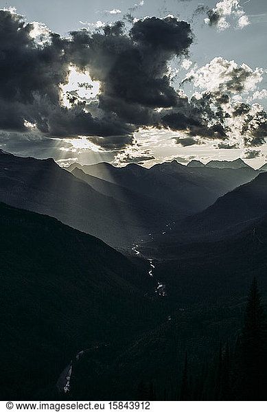 Sun bursts through clouds in mountain valley  Glacier National Park