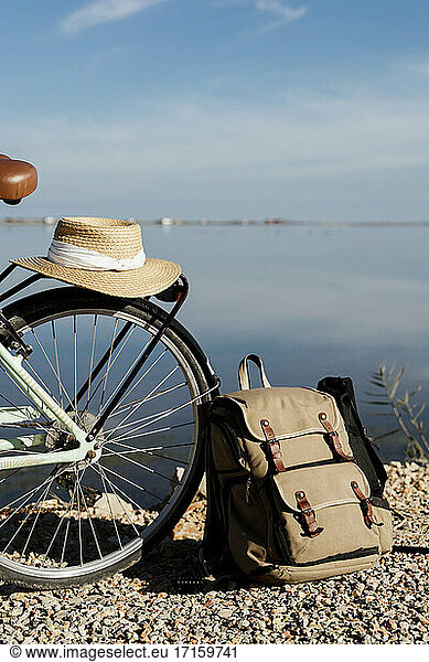 Sun hat kept on bicycle by backpack against sky on sunny day at Ebro Delta  Spain