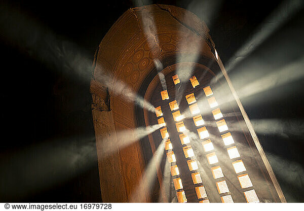 Sun rays going through arch window inside temple filled with smoke  UNESCO  Bagan  Mandalay Region  Myanmar