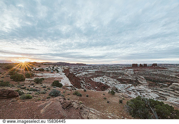 sun rises over a sea of canyons and red rock cliffs of The Maze Utah