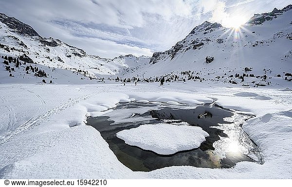 Sun shines over snow-covered mountain peaks  gorge peaks and heads of the Tarn Valley  in front open snow cover with water  Wattentaler Lizum  Tuxer Alps  Tyrol  Austria  Europe