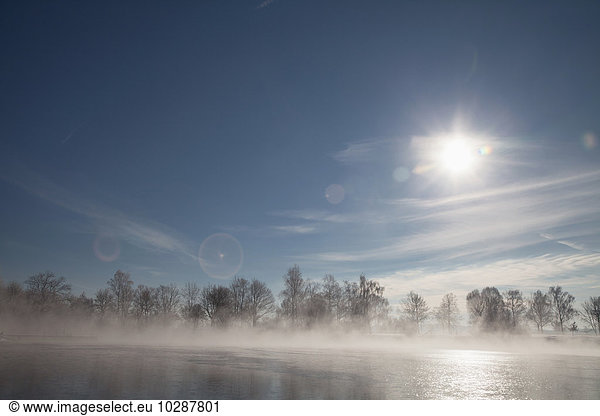 Sun shining over lake in winter  Eichenau  Fürstenfeldbruck  Bavaria  Germany