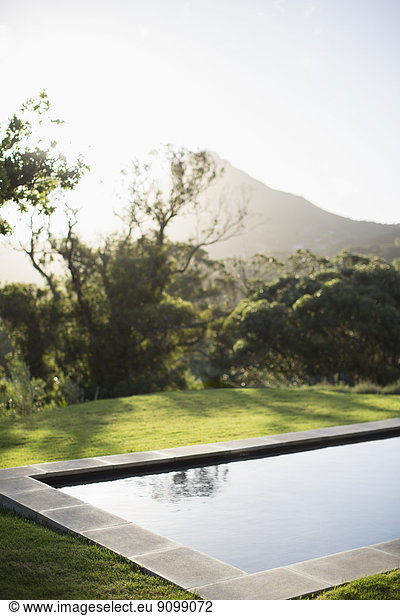 Sun shining over mountain and luxury lap pool